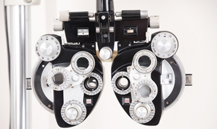 Phoropter eye exam device with multiple dials and lenses for measuring vision.