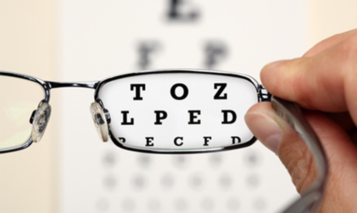 Glasses in focus with an eye chart reading TOZ, LPED, PECFD, blurred in the background.