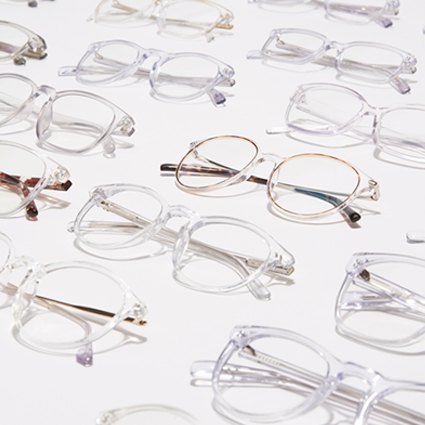 Various clear and metal-framed eyeglasses arranged on a white surface.