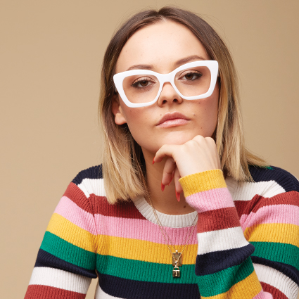 White-framed cat-eye glasses worn by a person in a colorful striped sweater.