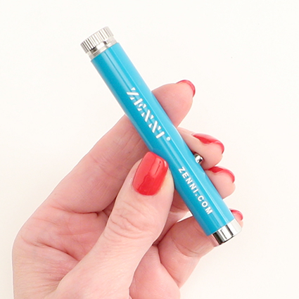 Blue laser pointer with silver details being held in a hand with red-painted nails. Text: "ZENNI ZENNI.COM."