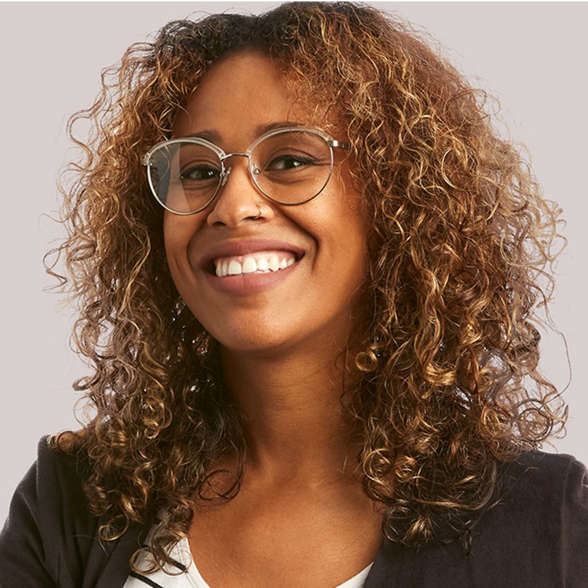 Woman wearing round, thin metal-framed glasses smiling.