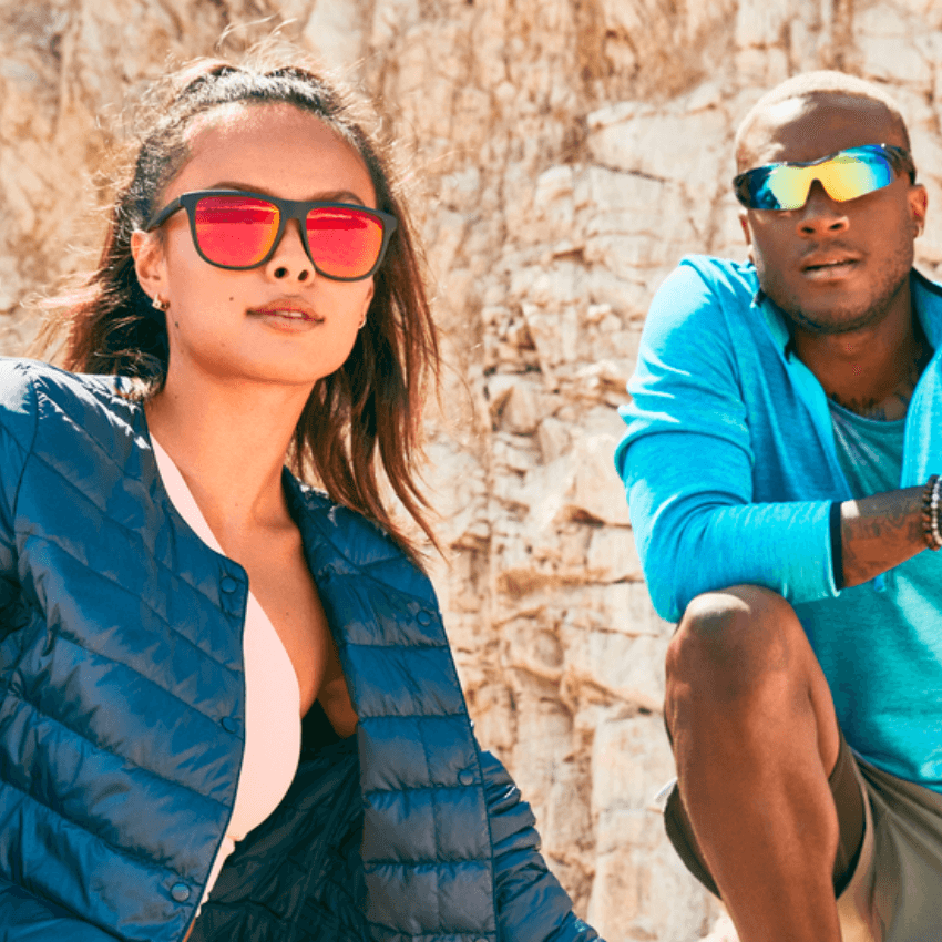 Two people wearing reflective sports sunglasses; one wears a blue jacket, the other wears a blue shirt.