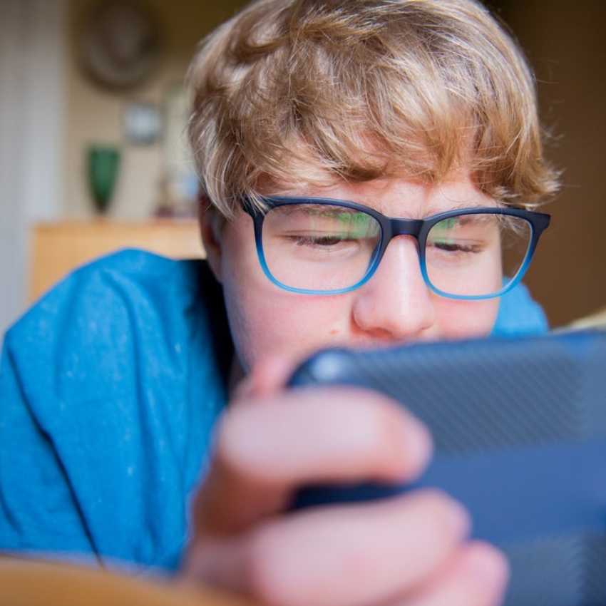 Person wearing two-tone glasses looking closely at a phone screen.