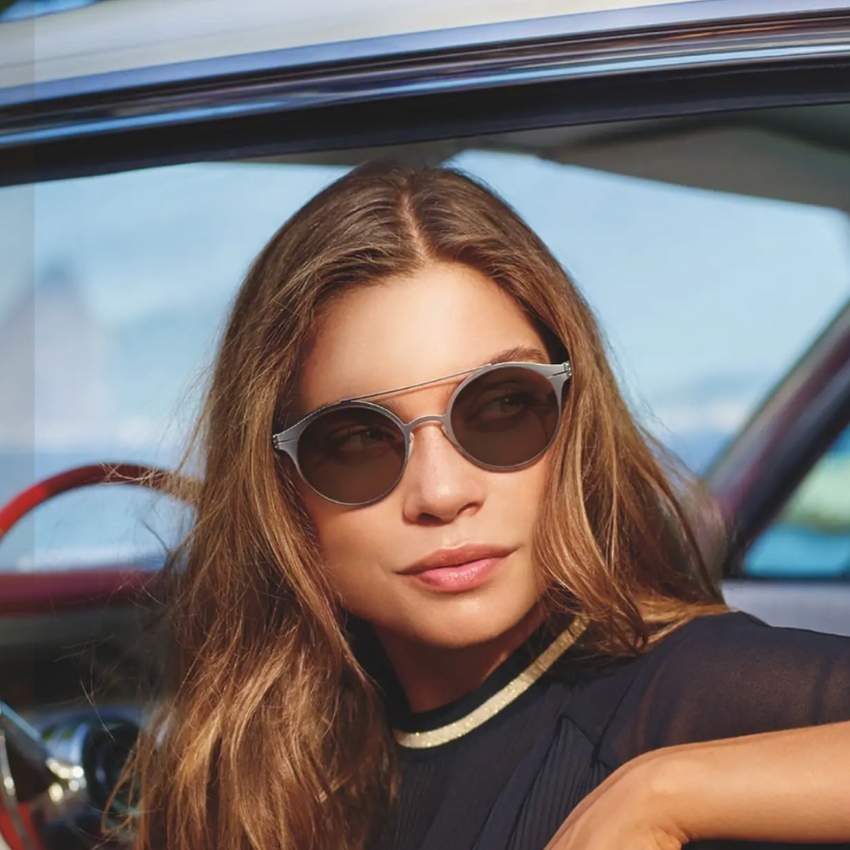 Woman wearing sleek, modern sunglasses with silver metallic frames and dark lenses.