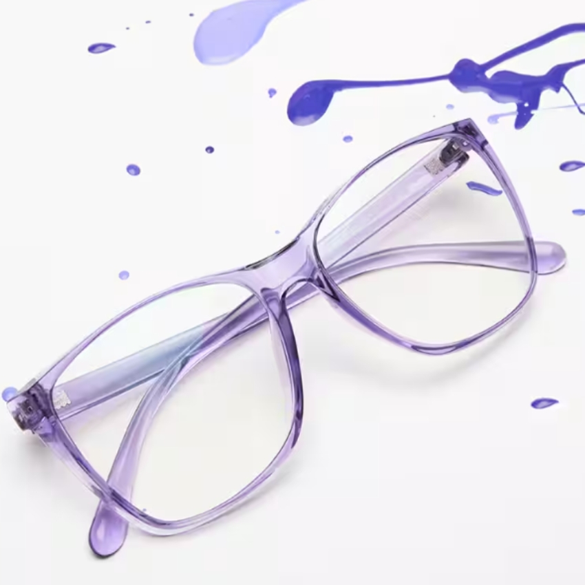 Purple transparent eyeglasses with an oversized frame, placed on a white surface with blue paint splatters.