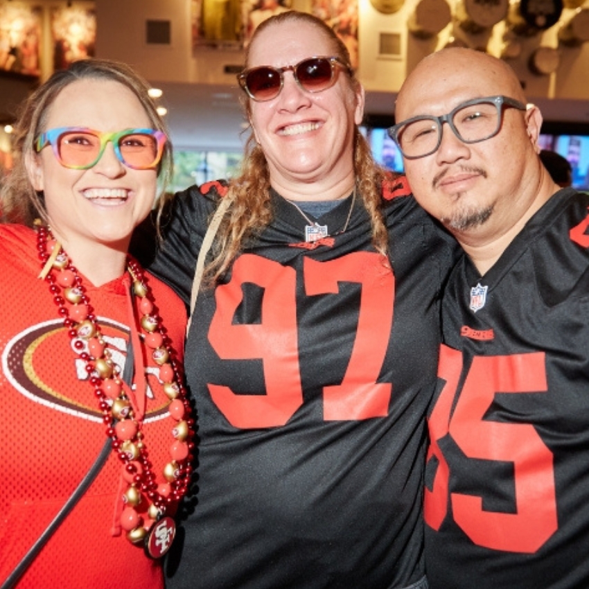 Three people wearing San Francisco 49ers jerseys, numbers 97 and 85 seen clearly.