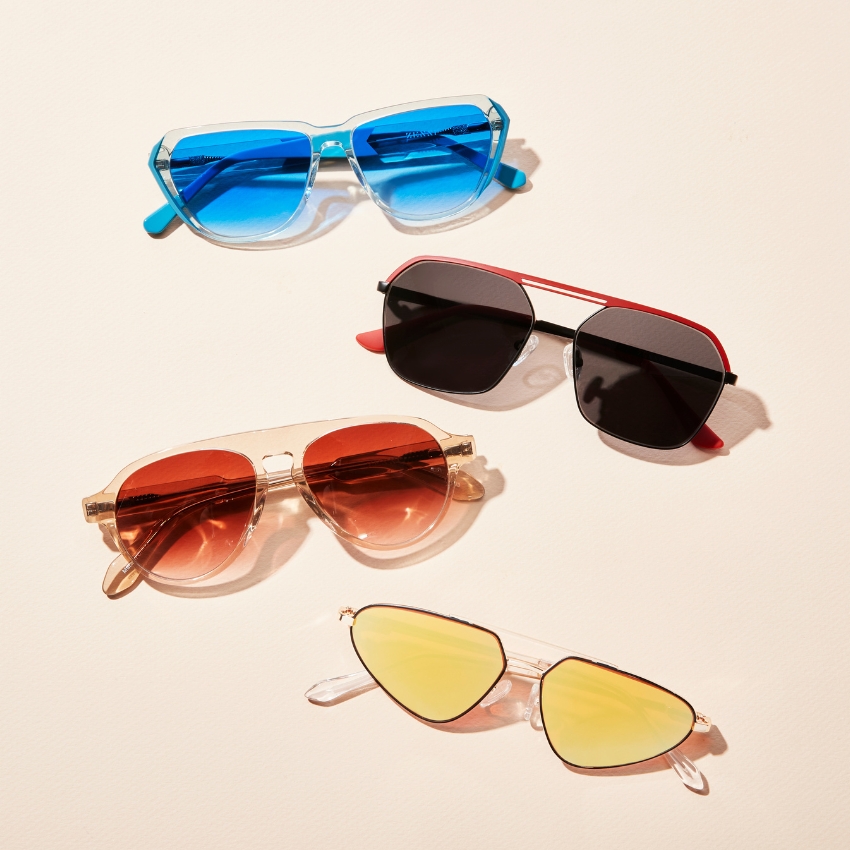 Four pairs of sunglasses with colored lenses: blue, black, orange, and yellow.