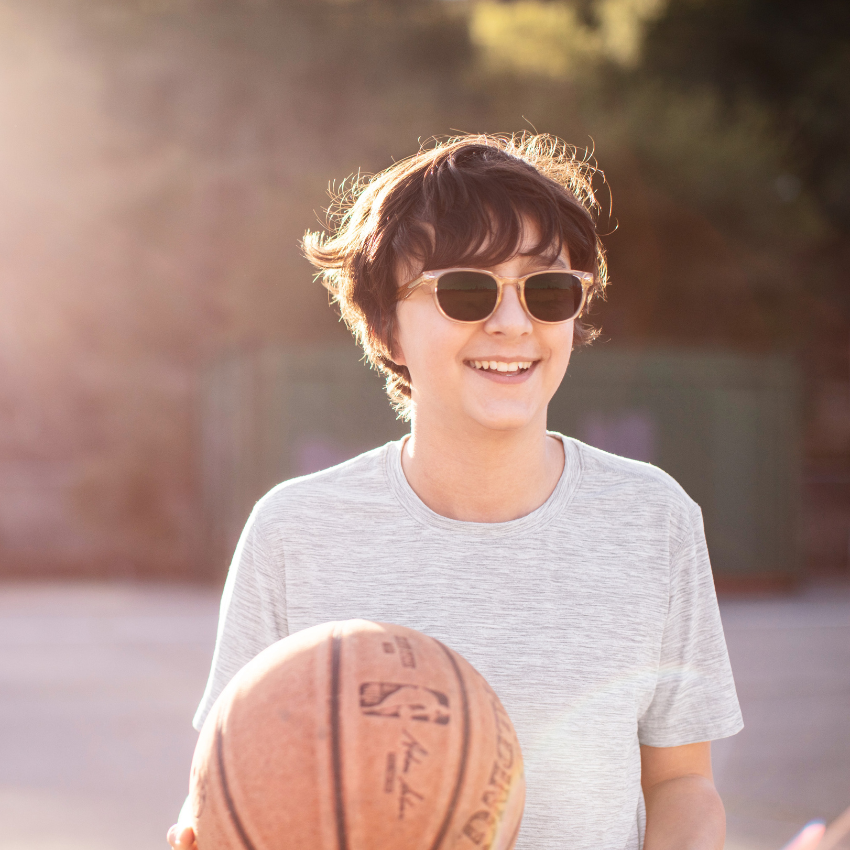 Person wearing sunglasses holding a Spalding basketball imprinted with "NBA" and Spalding logo.