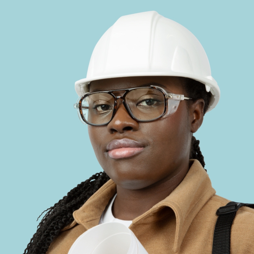 Person wearing a white hard hat and glasses, holding rolled-up papers.