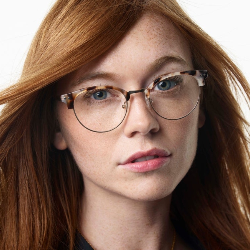 Woman wearing tortoiseshell round eyeglasses with metal bridge and clear nose pads.