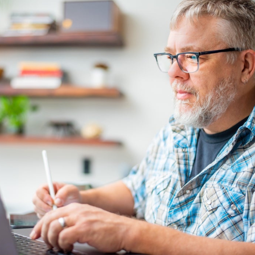 Man wearing glasses using a stylus on a tablet.