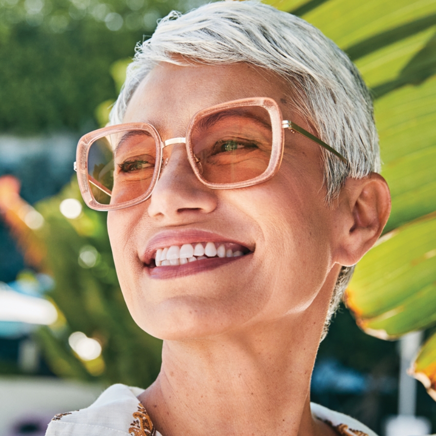 Person wearing pink oversized square sunglasses with tinted lenses.