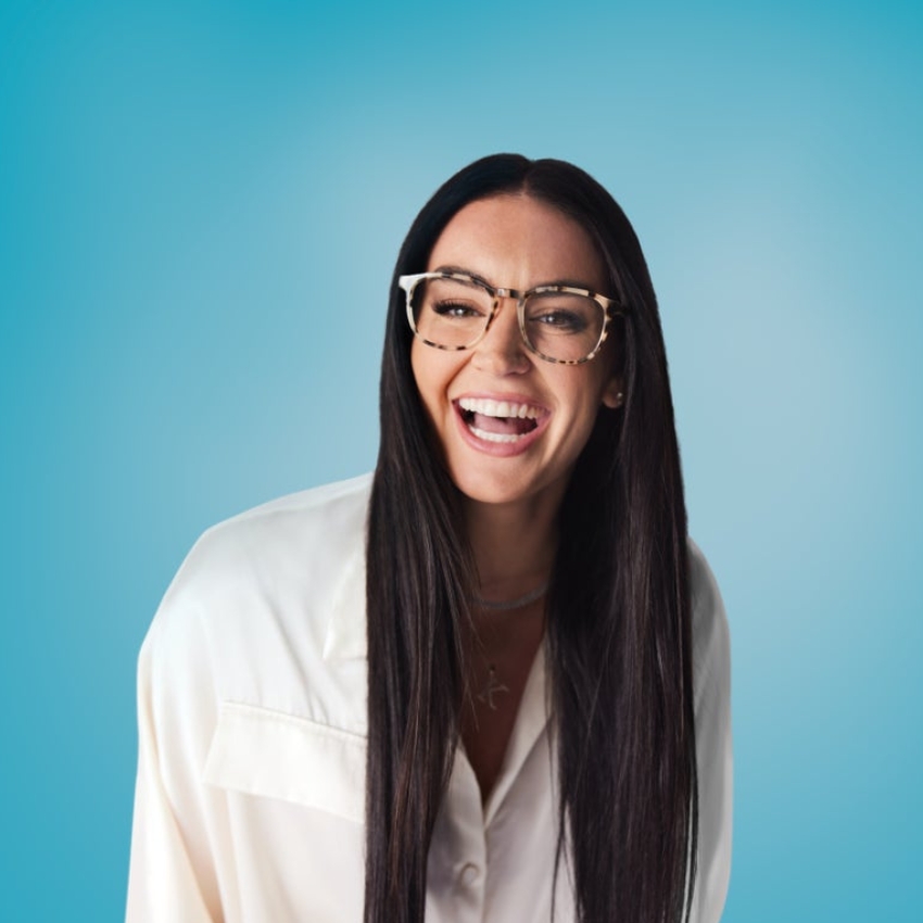 Woman wearing large, tortoiseshell eyeglasses, smiling widely.