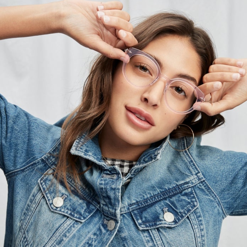 Clear round glasses with thin frames being modeled by a person wearing a denim jacket.