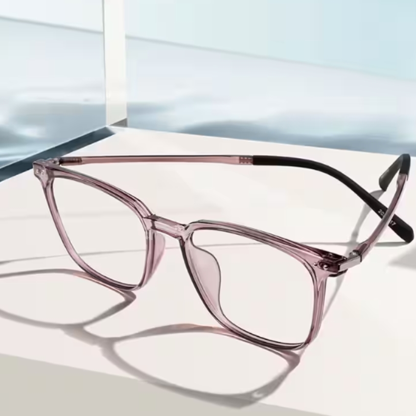 Translucent pink eyeglasses with black temple tips, displayed on a white surface.