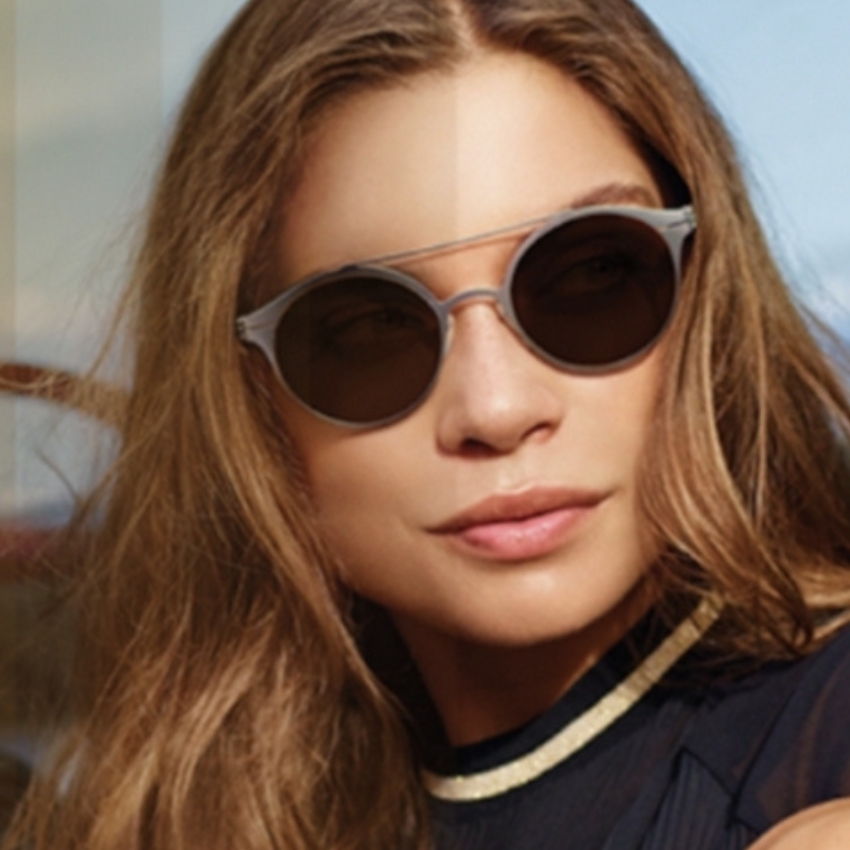 Woman wearing stylish round sunglasses with silver frames and dark lenses.