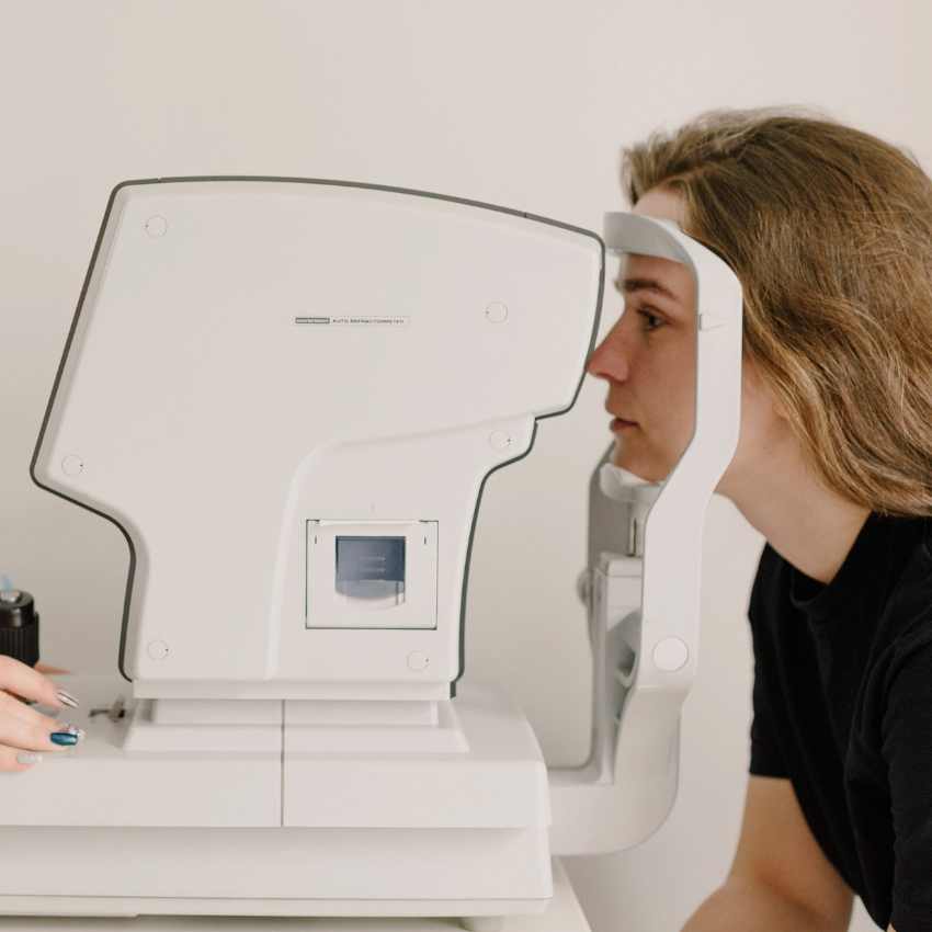 Woman undergoing an eye exam using an auto refractometer.