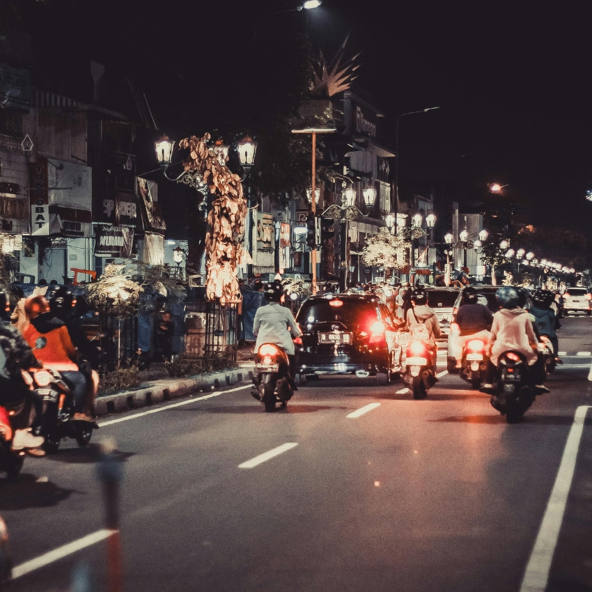 Motorcycles and cars on a busy city street at night, with streetlights illuminating the scene.