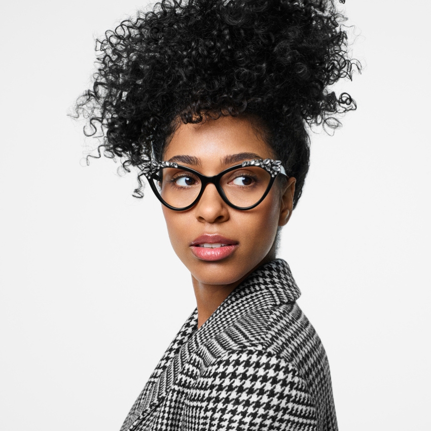 Woman wearing black cat-eye glasses with white pattern detailing, dressed in black and white houndstooth jacket.