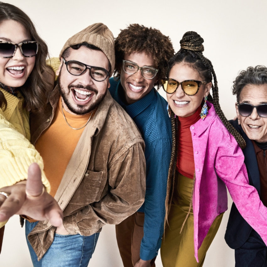 Group of people wearing various stylish glasses, smiling and posing energetically towards the camera.