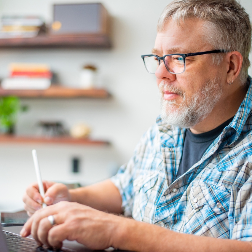 Person using a laptop and stylus.