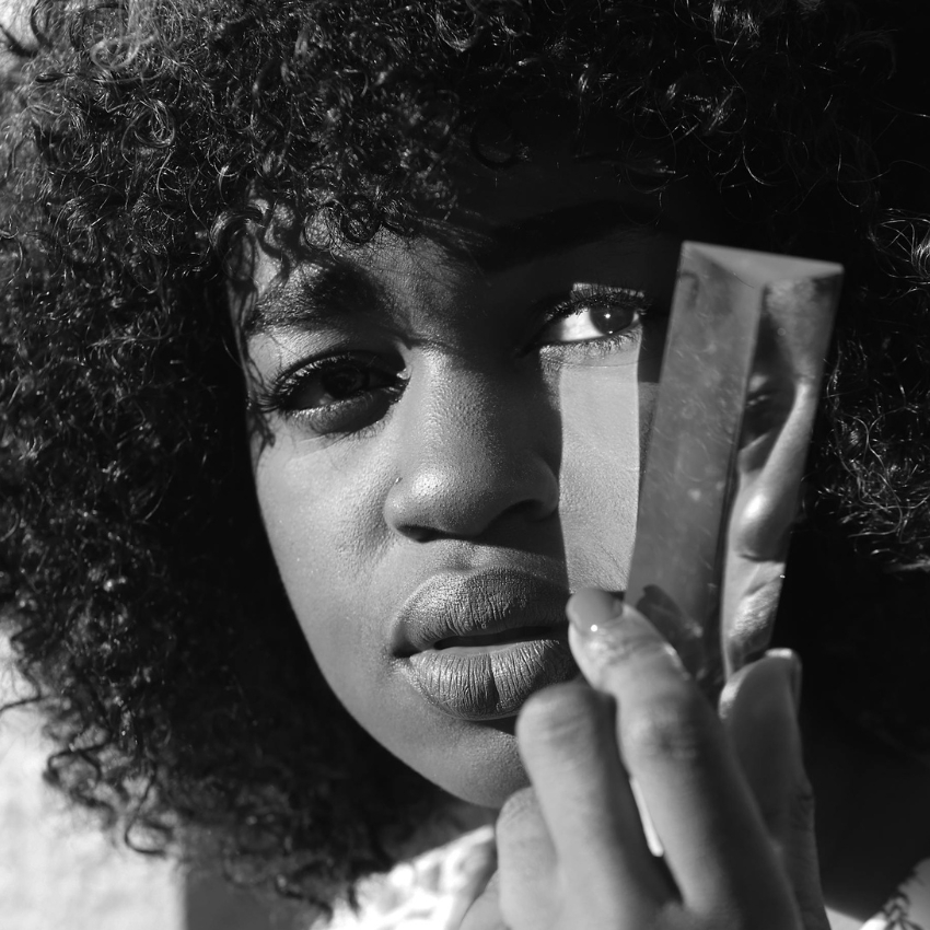 Woman holding a reflective prism close to her face.