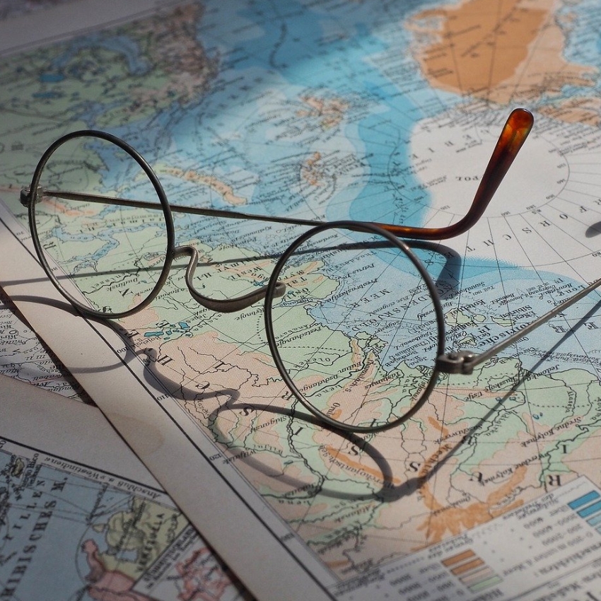 Round, wire-framed spectacles on a world map background.