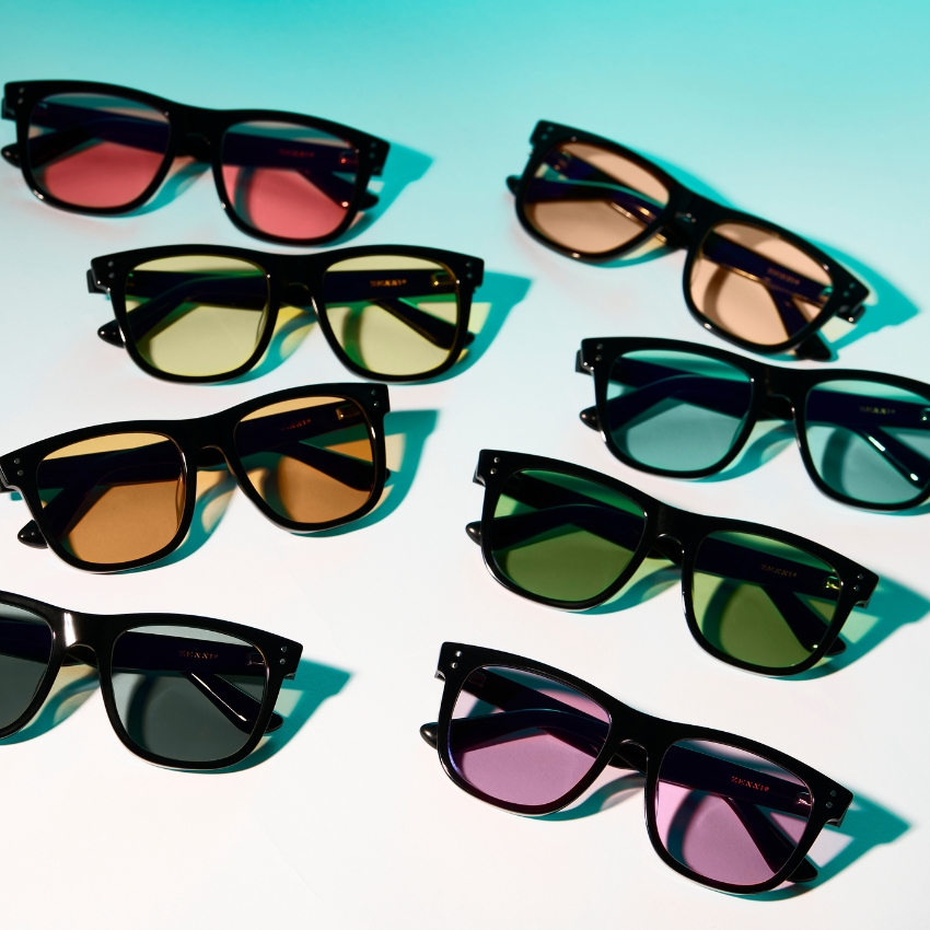 Various sunglasses with black frames and lenses in colors including pink, yellow, green, blue, and brown.