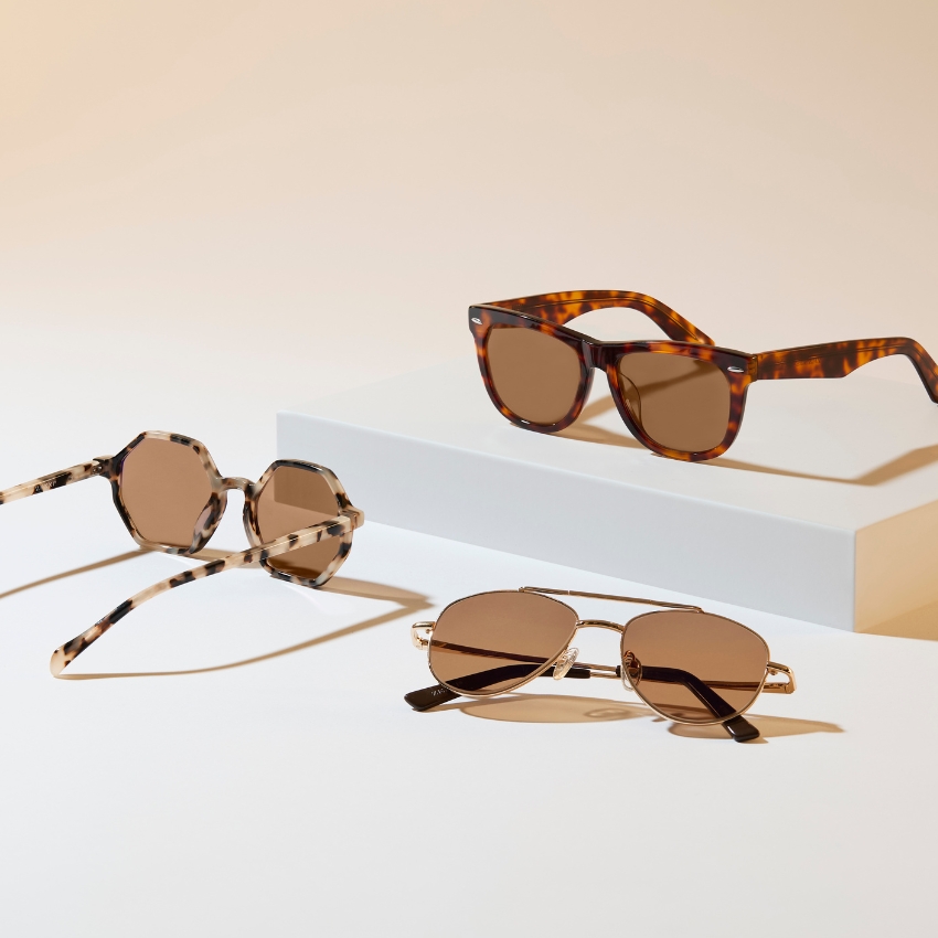 Three pairs of brown-tinted sunglasses with tortoiseshell and gold frames on a white surface.