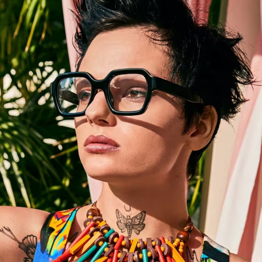 Woman wearing large black glasses and a colorful beaded necklace.