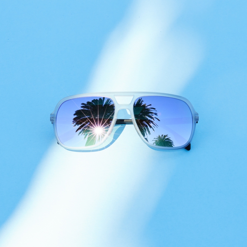 Sunglasses with palm tree reflections in blue-tinted lenses.