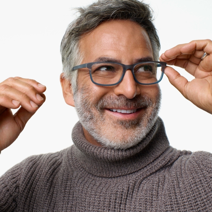 Man adjusting his sleek, rectangular glasses while wearing a gray turtleneck sweater.