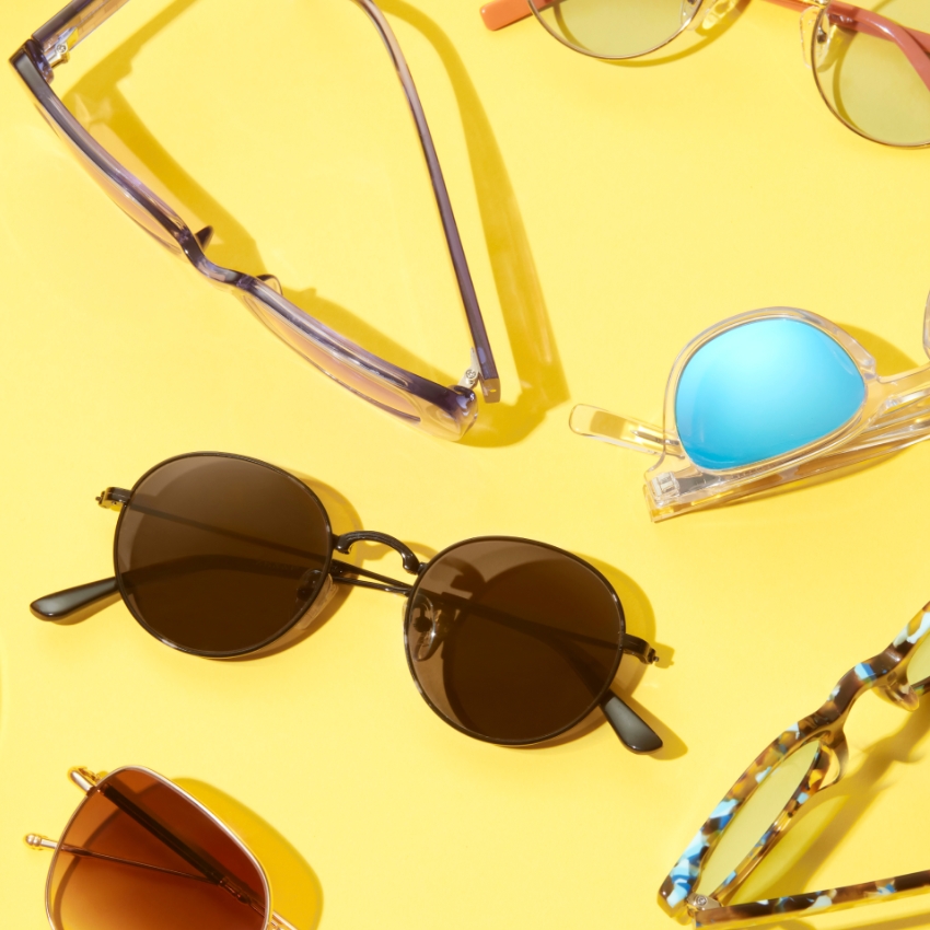 Various styles of sunglasses arranged on a yellow surface.