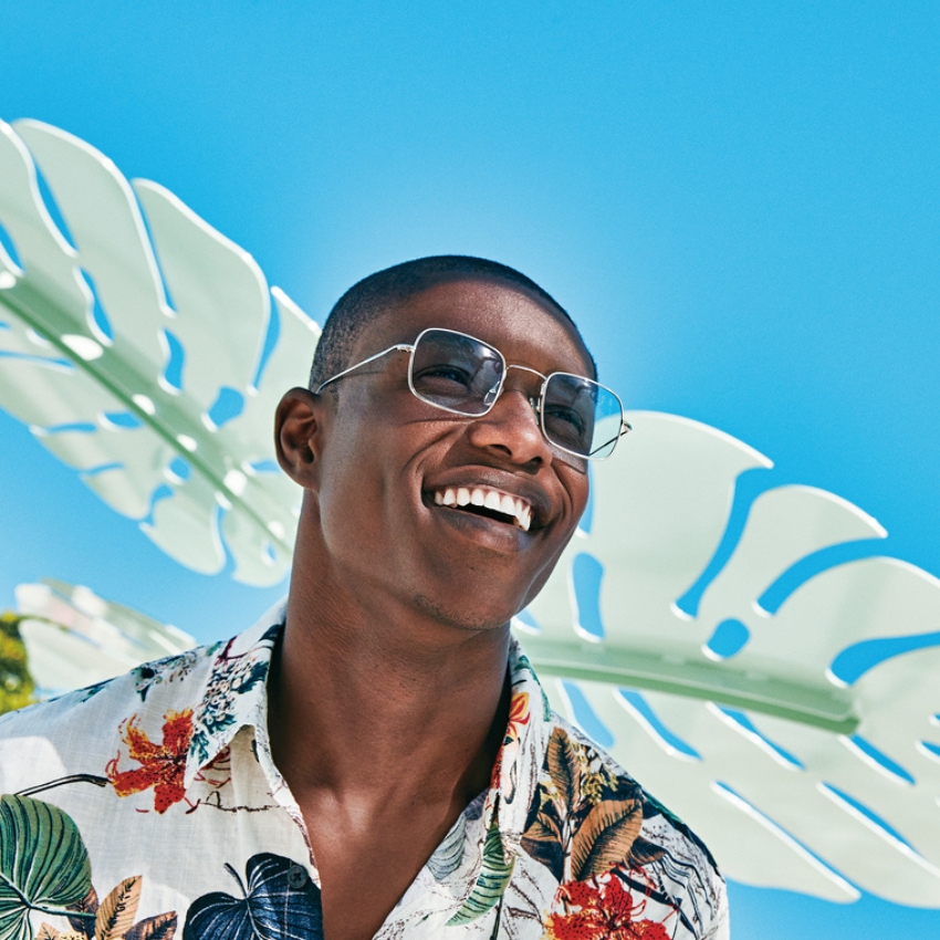 Man wearing square aviator sunglasses and a floral print shirt.