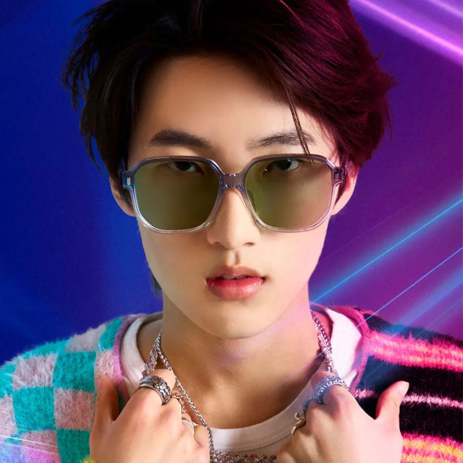 Person wearing oversized, translucent sunglasses with green lenses and multiple rings, posing confidently.