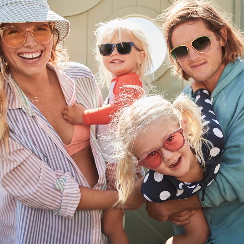 Family wearing sunglasses and swimwear in a joyful moment.