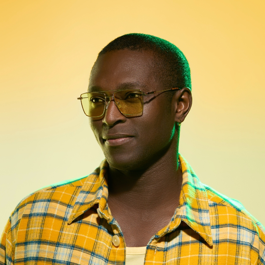 Man wearing gold-tinted aviator sunglasses and a yellow plaid shirt.