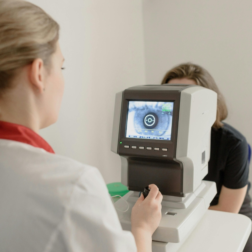 Optometrist using an autorefractor machine with an eye image on the screen.