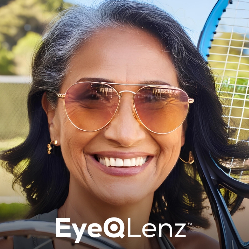 Woman wearing EyeQLenz sunglasses, smiling. Holding a tennis racket on her shoulder.