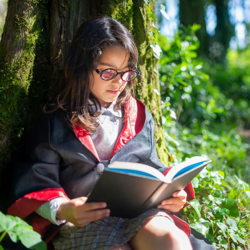 Child in wizard outfit reading a book.