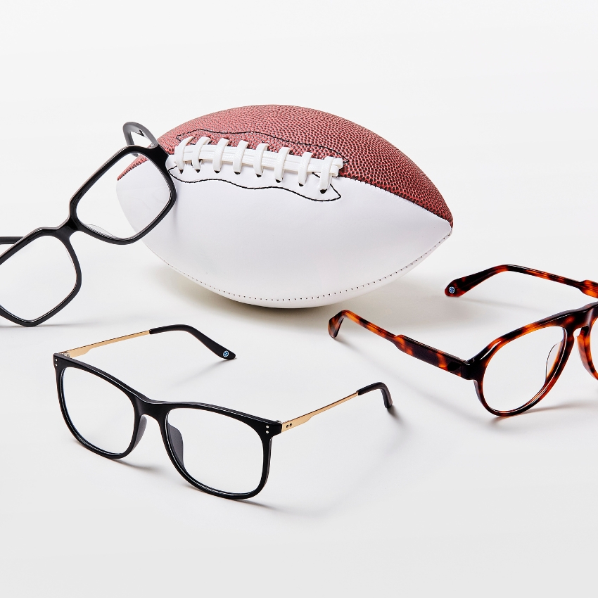 Three pairs of eyeglasses in different styles next to an American football.