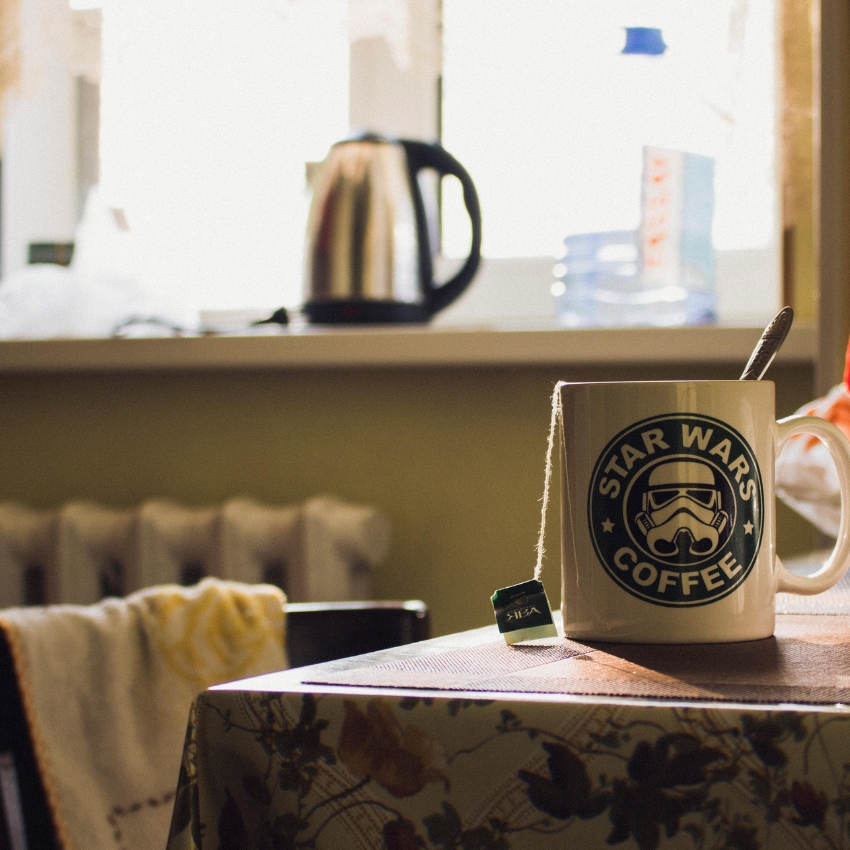 White mug with "STAR WARS COFFEE" and a Stormtrooper helmet logo. A tea bag labeled "TEEKANNE" hangs out.