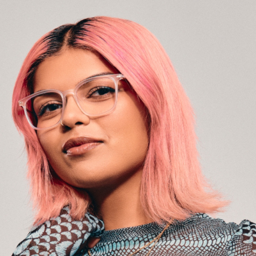 Person wearing clear-framed glasses with light pink hair.