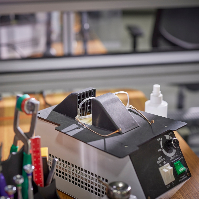 Eyeglass cleaning and sanitizing machine with control dials and air vents, surrounded by tools.