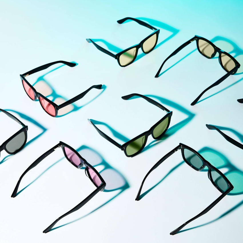 Assorted sunglasses with black frames and various lens colors including pink, green, and brown.