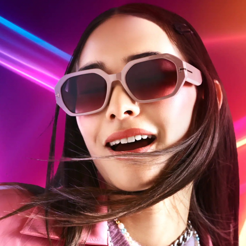 Woman wearing large, rectangular, pink sunglasses with dark lenses.