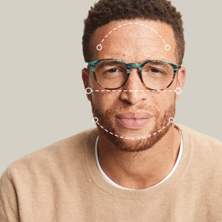 Man wearing tortoiseshell glasses with green accents, overlayed with facial measurement lines for a perfect fit.