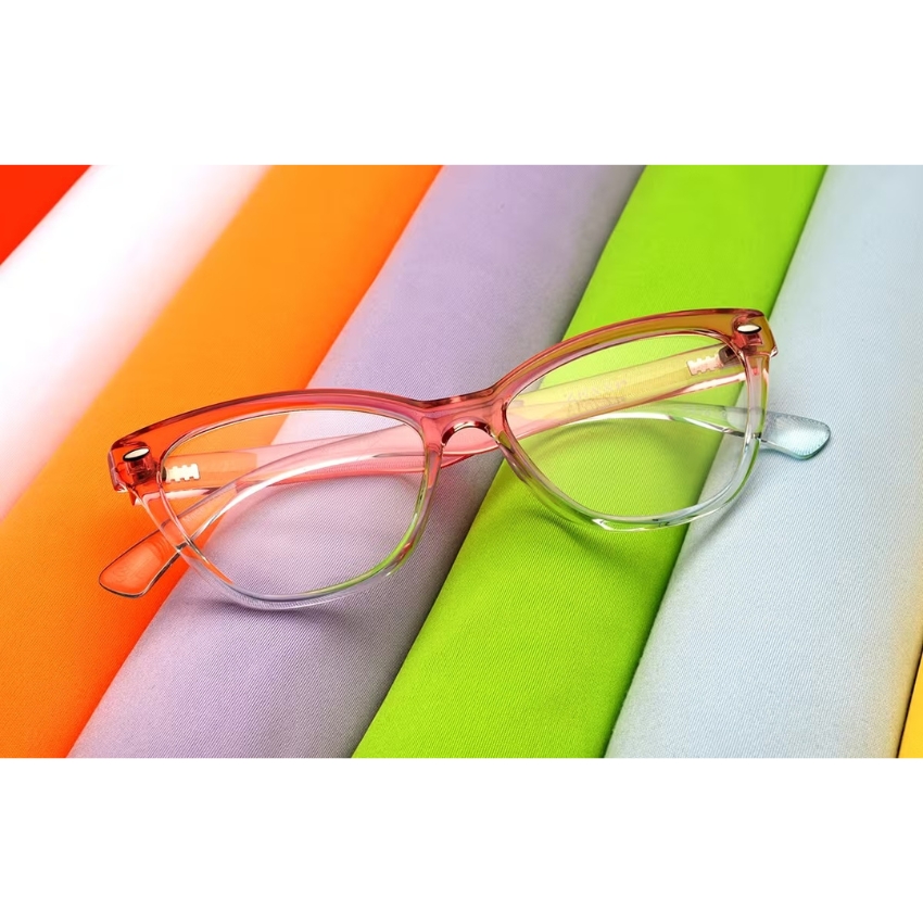 Translucent pink glasses frame with a cat-eye shape, displayed on six colorful fabric swatches.