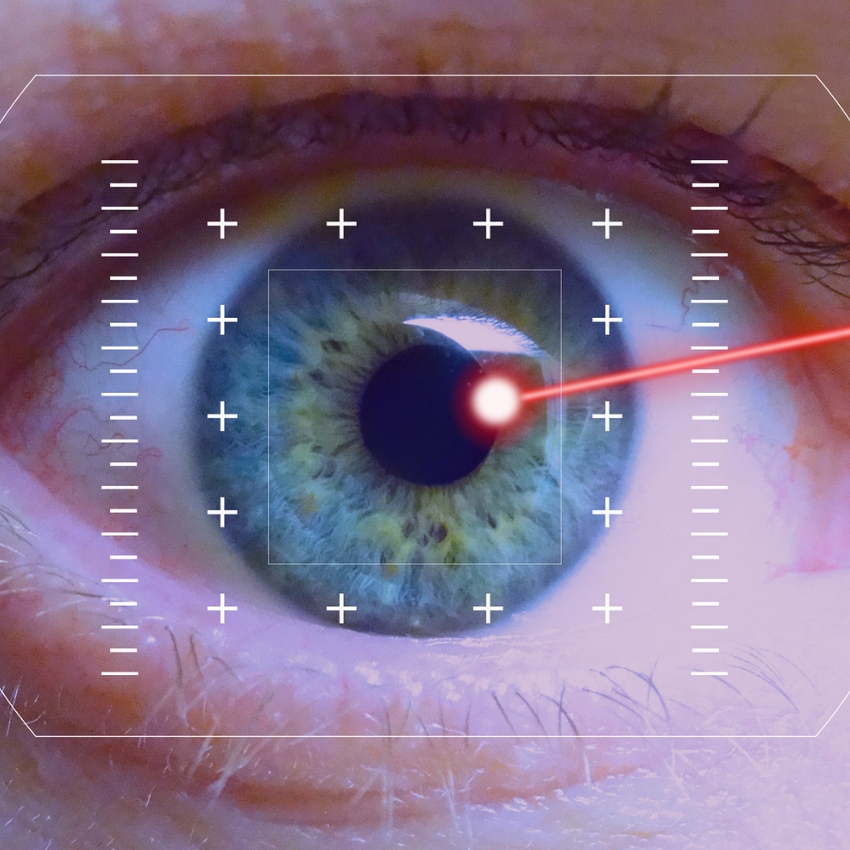 Eye undergoing laser treatment with targeting system overlay and red laser beam aiming at pupil.